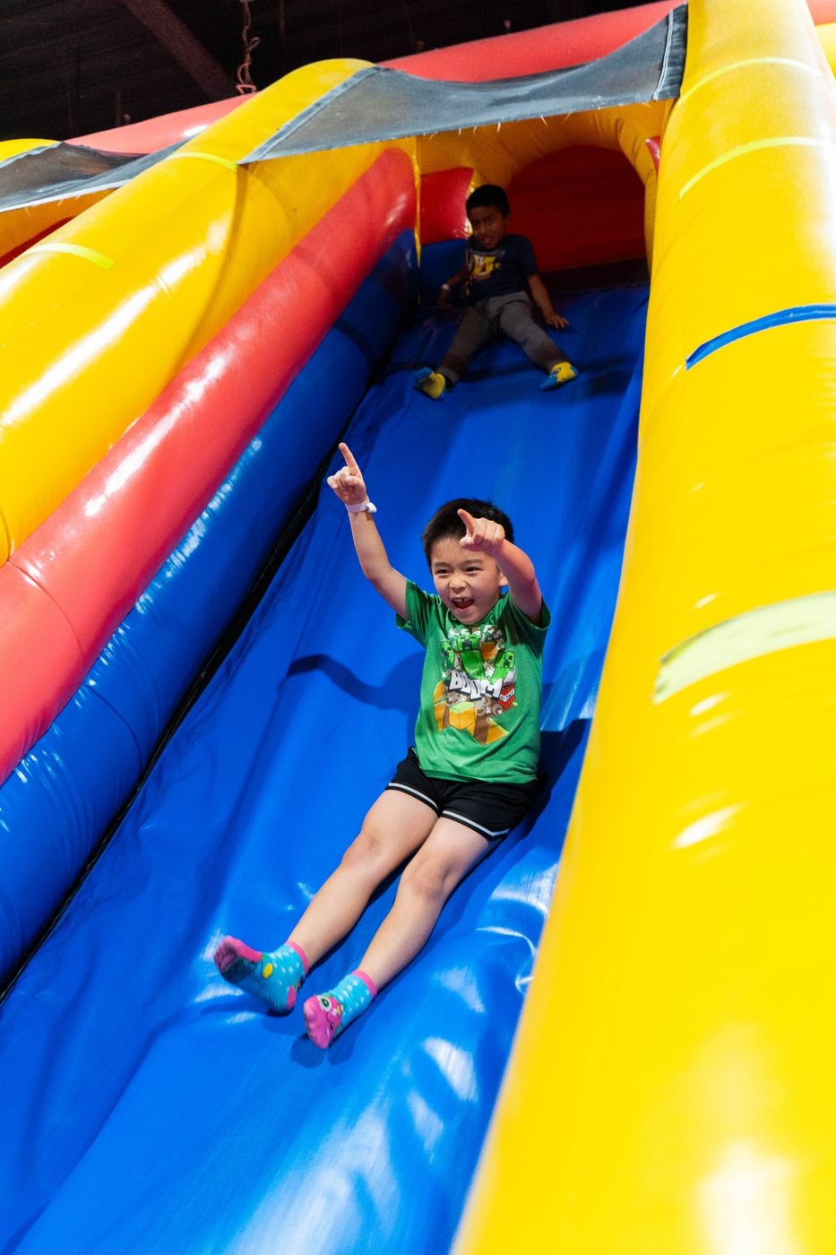 Boy sliding down a giant blue inflatable slide at FUNBOX