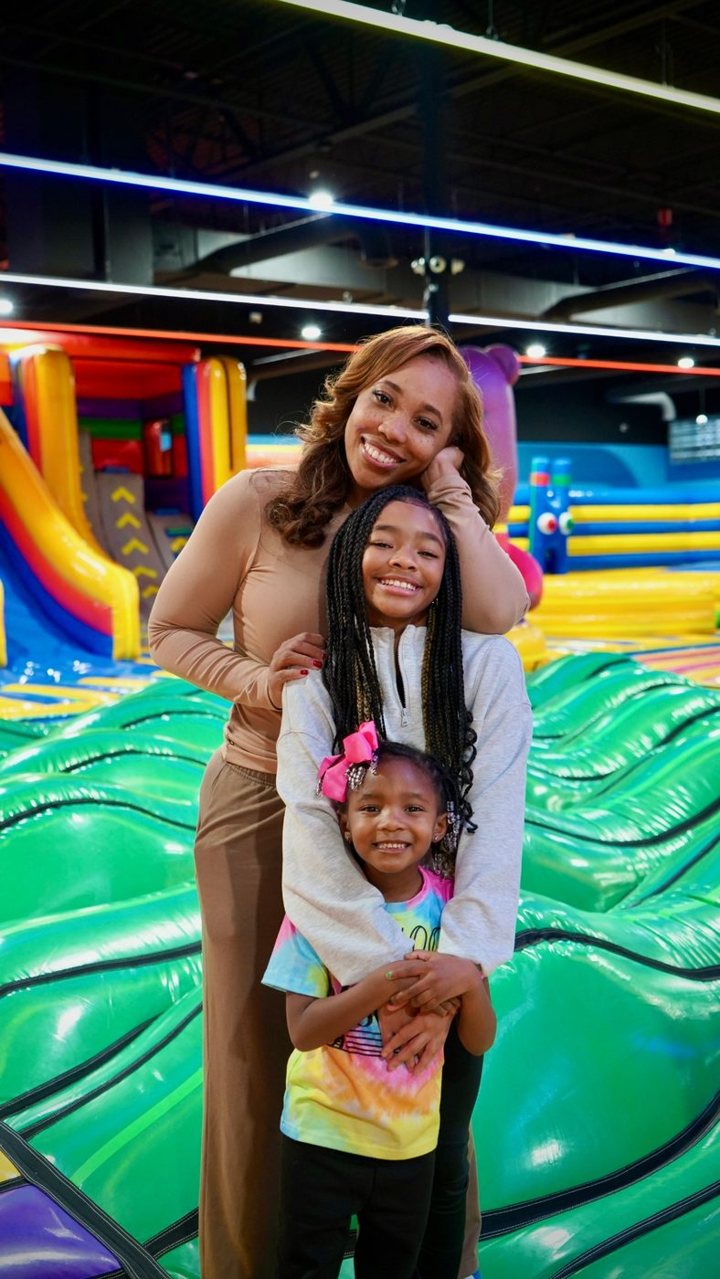 Mom and two daughters smiling on the bounce park