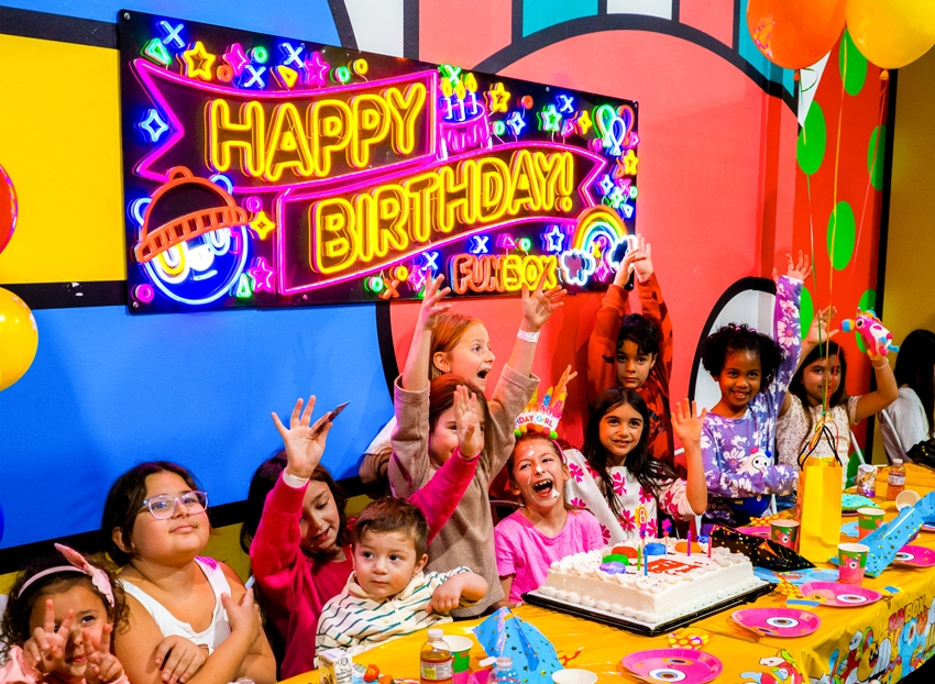 Kids celebrating under the neon HAPPY BIRTHDAY sign in a FUNBOX party room
